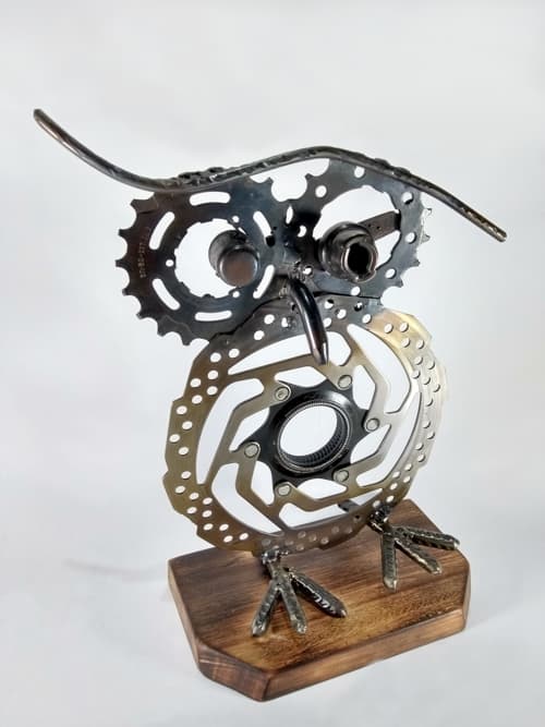 Un disco de freno y varias piezas reutilizadas conforman esta pieza única. El metal está tratado con un proceso de pavonado y la base con efecto quemado está lustrada con cera incolora. 