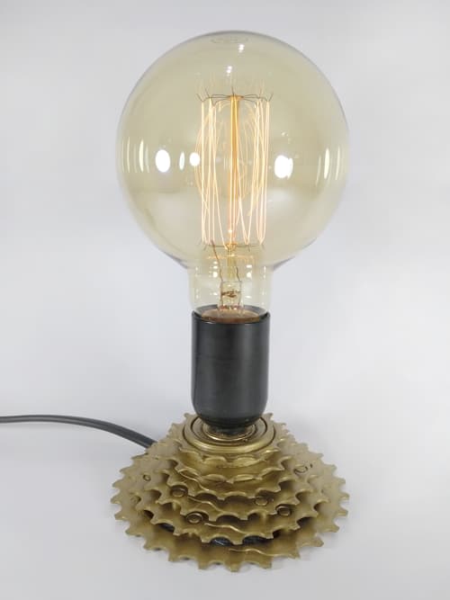 Lámpara estilo vintage realizada con un piñón totalmente reciclado. Se desarmó, limpió y se volvió a ensamblar. Se soldó para evitar el giro, luego se pintó. Se realizó la instalación eléctrica estañando todos los contactos y por último se diseñó a medida una cuerina que se pegó en la base. Posee dimer y un foco globo que la hacen única.