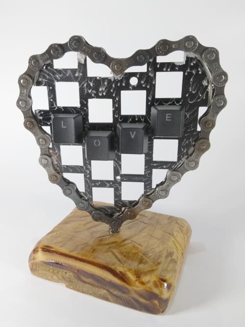 Realizado con partes de un teclado sin funcionar y cadena reciclada de bici, madera recuperada.  Las teclas forman la palabra LOVE. Posee un baño de barniz protector.
