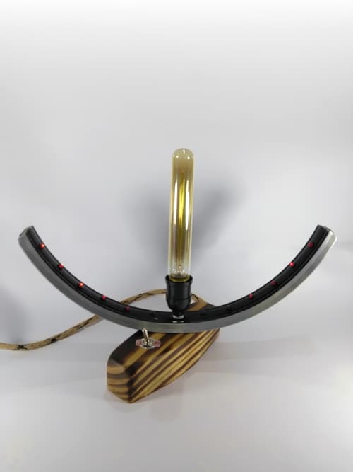 Lámpara decorativa realizada totalmente de forma artesanal, desde la base cortada, lijada y encerada a mano (efecto quemado), hasta los 12 leds de alta luminosidad colocados uno por uno en los orificios de la rueda de bicicleta. Completa este adorno el cable de yute con detalles en negro. Un sólo switch que enciende, apaga y selecciona el tipo de iluminación. Regalate algo original para decorar tu habitación.