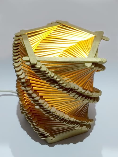 Velador original con 225 palitos dorados, colocados y encolados de forma artesanal sobre un pentágono de madera de 8,5cm. de lado y una lámpara dicroica led de bajo consumo, conforman esta hermosura.